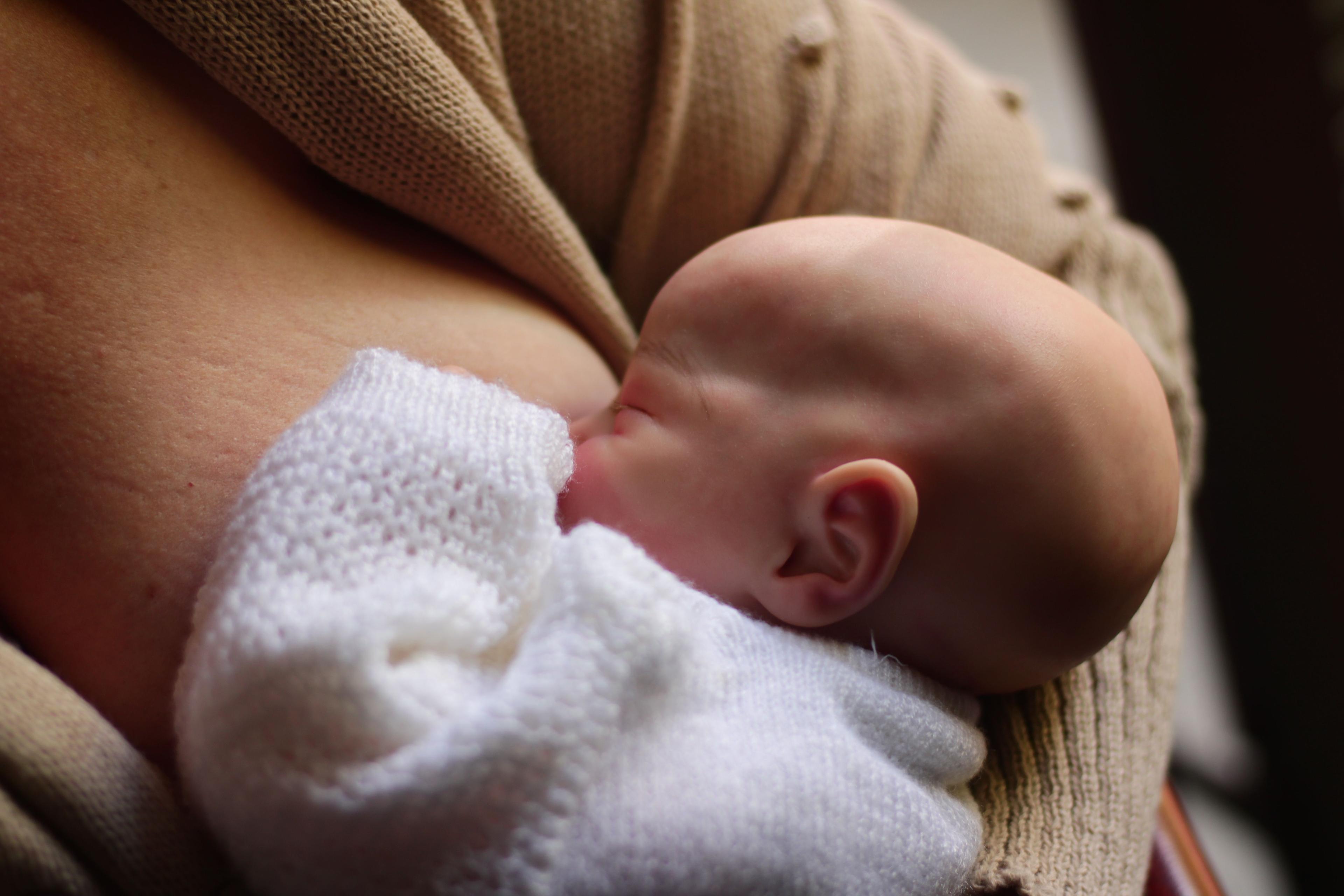 Close-up of a newborn breastfeeding in soft light.